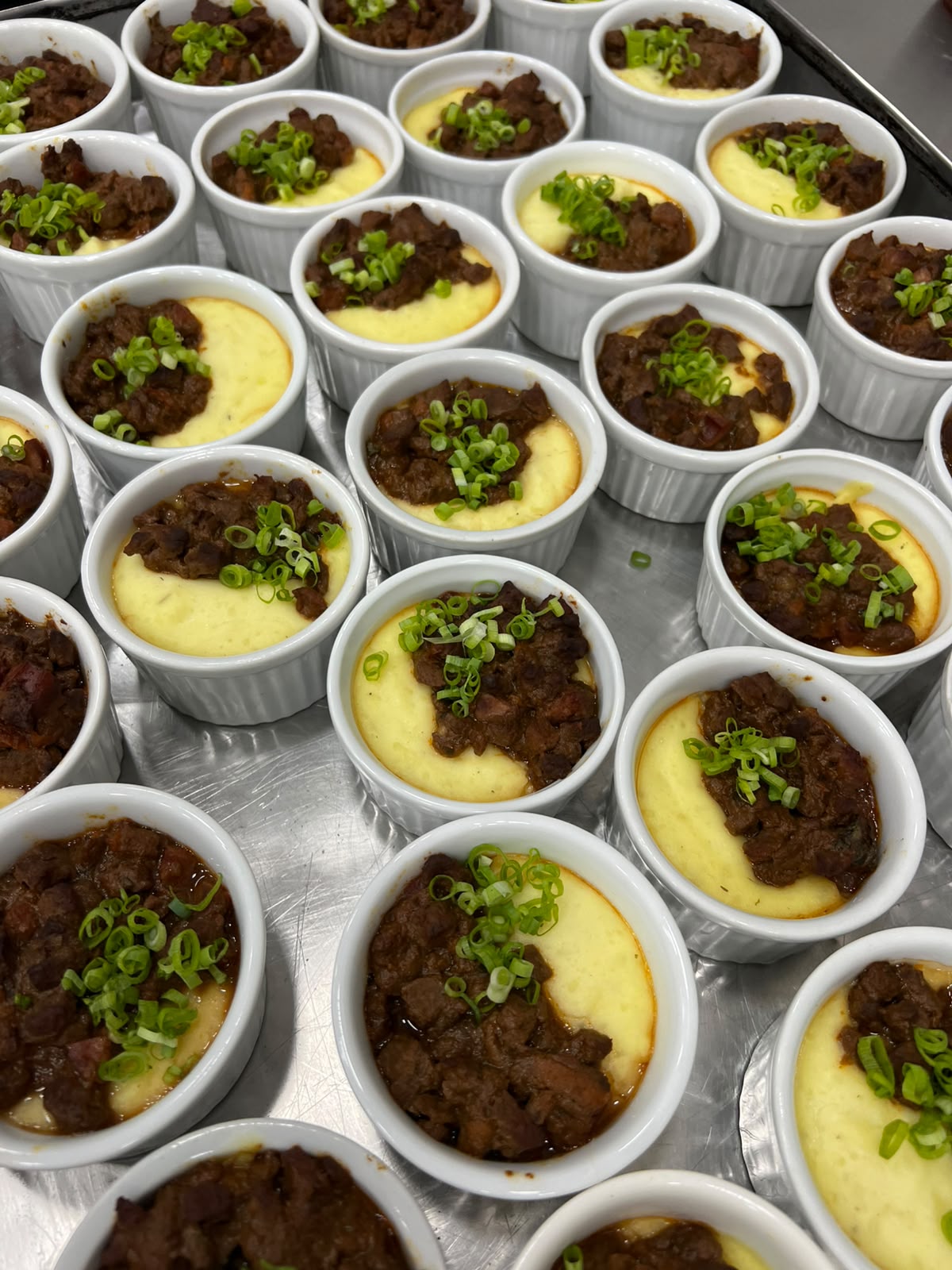 Porções de ragu de filé ao vinho com aligot e cebolinha preparadas pela Chef Helô para um evento